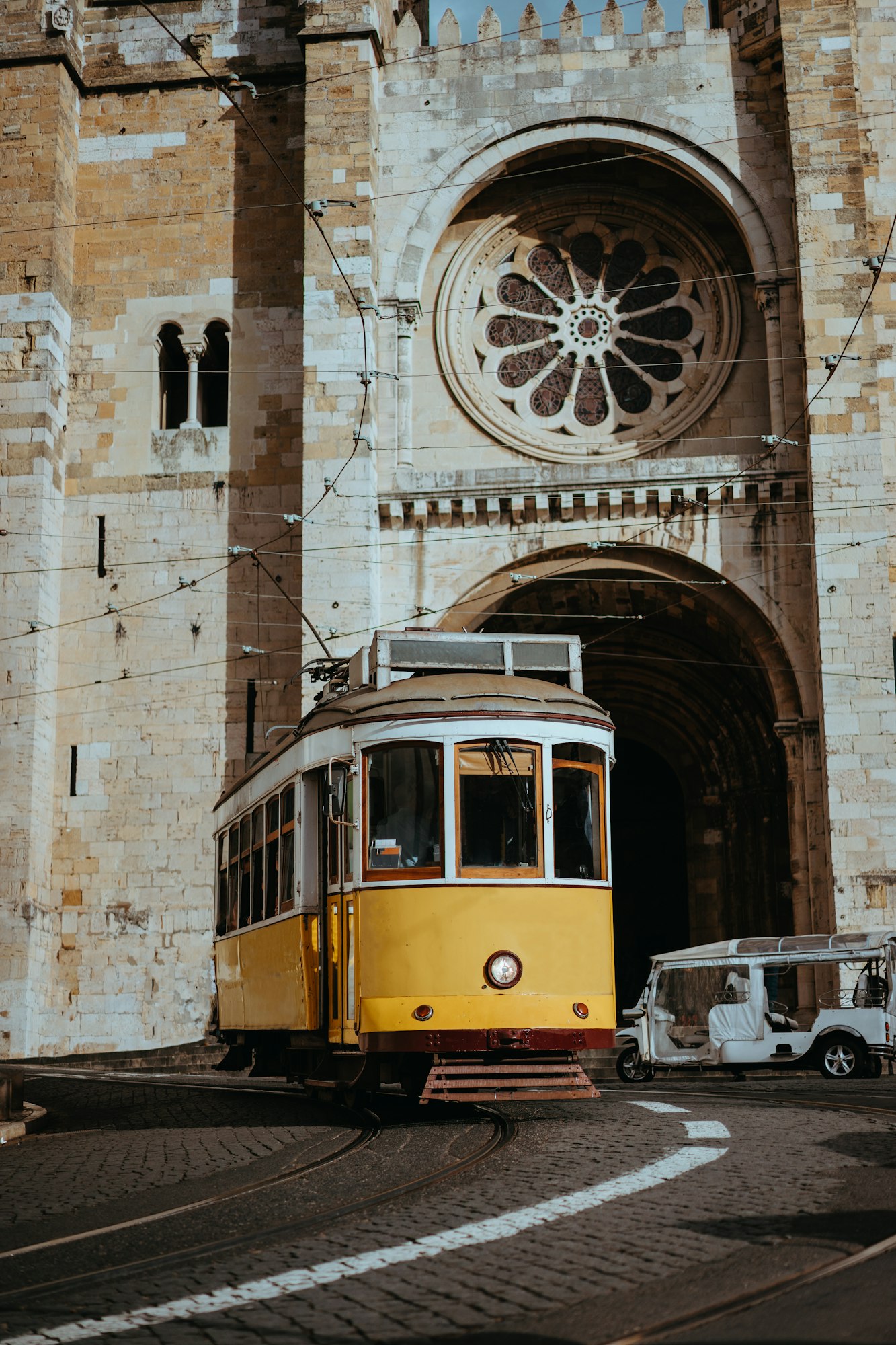 Quaint yellow tram passes directly in front of the Se Cathedral in Lisbon. Lisboa Lissabon